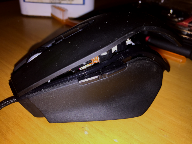The two plastic tabs on the front side of the top shell must be located before squeezing the back of the top shell over the catch on the rear side of the base of the Corsair M40 Raptor mouse